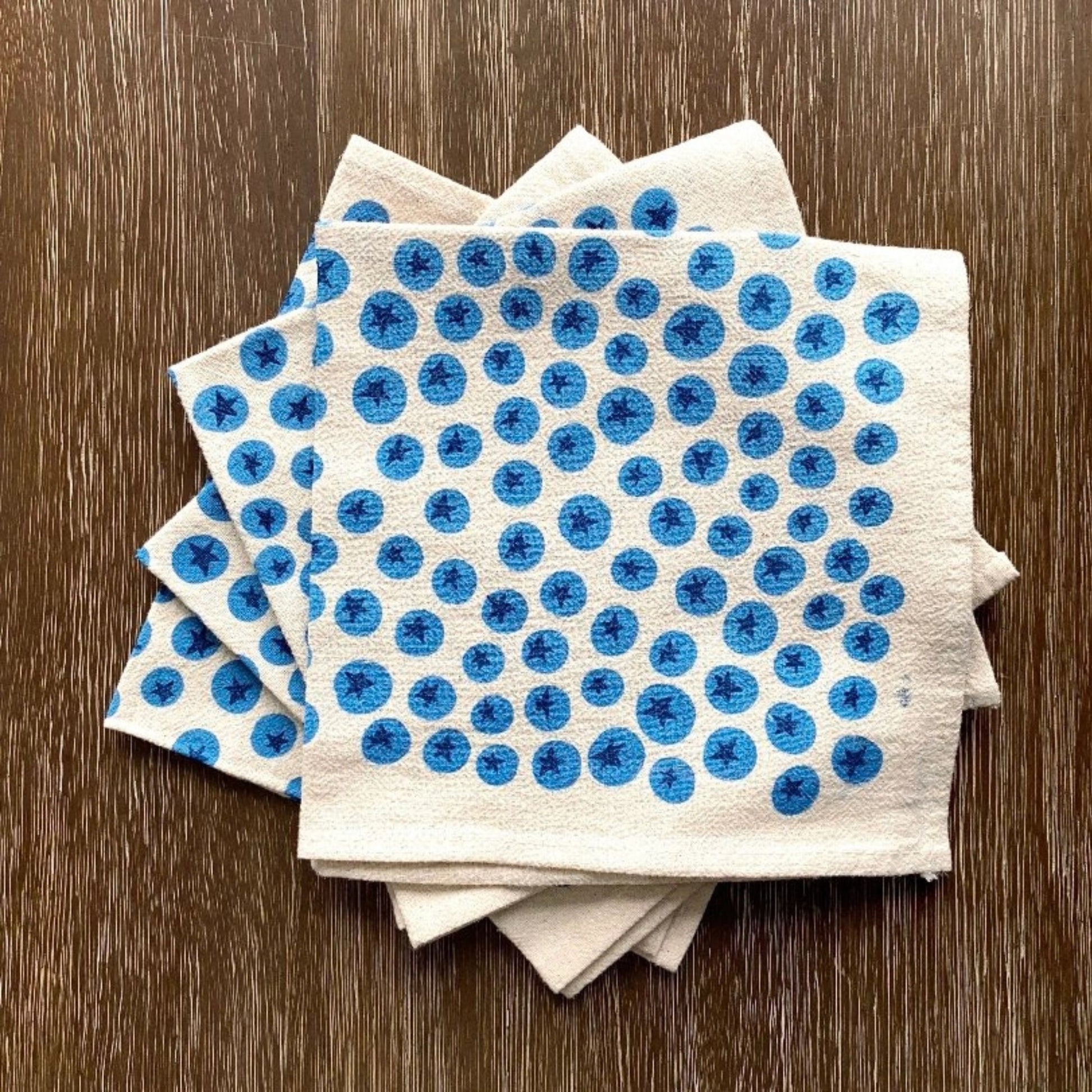 Stack of white cloth napkins with blueberry pattern on a wooden surface