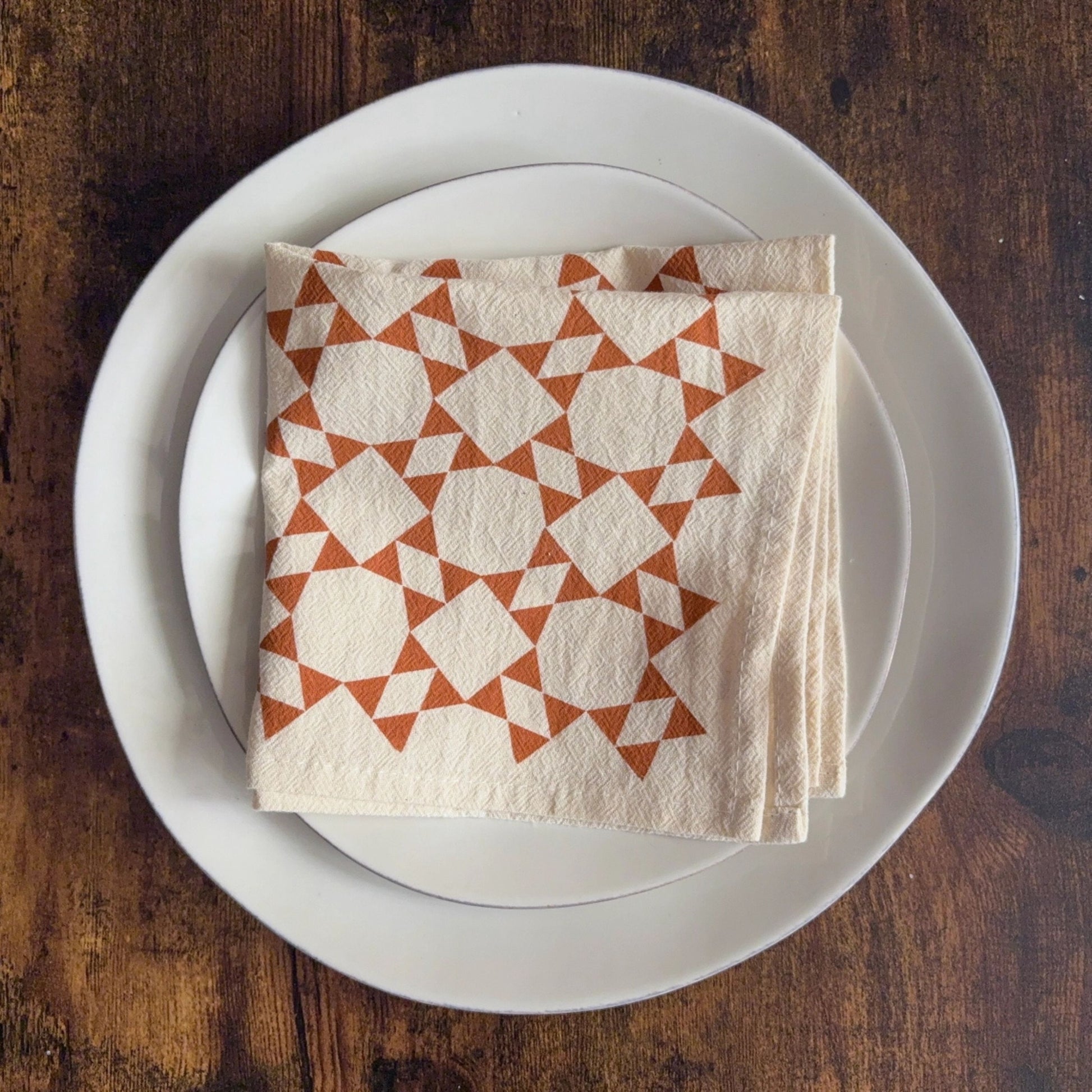Stack of patterned napkins on a white plate with a wooden background