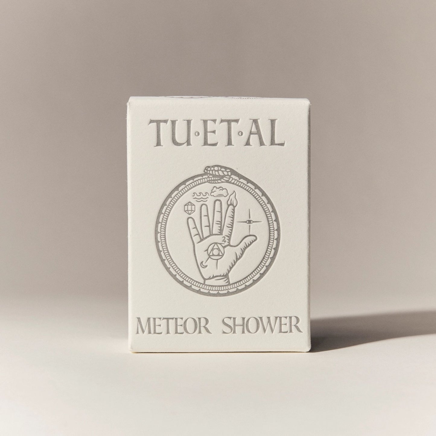 Box of bar soap packaging with 'TU.ET.AL' branding and hand design on a beige background