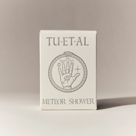 Box of bar soap packaging with 'TU.ET.AL' branding and hand design on a beige background