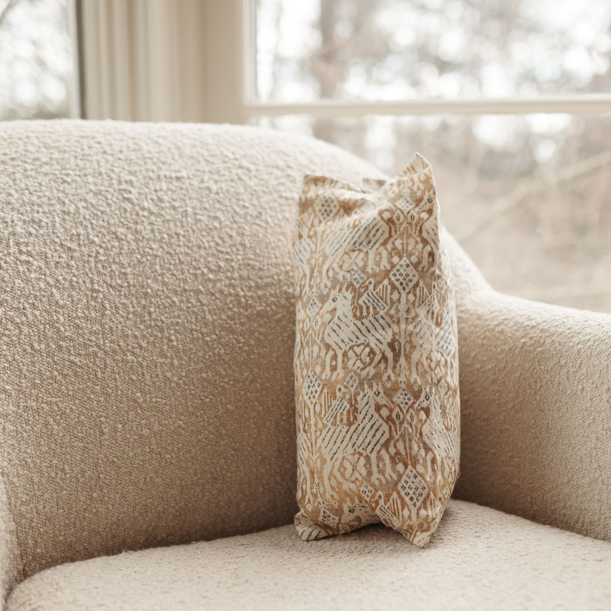 Buckwheat Pillow with abstract golden pattern resting on a sofa. The cover is 100% linen.