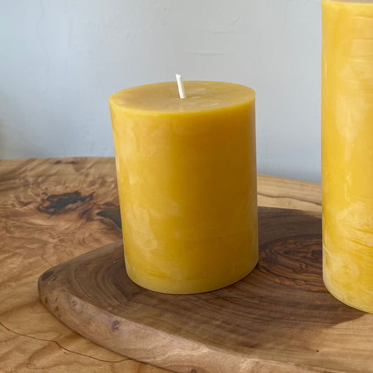 4 inch beeswax candle on a wooden plate