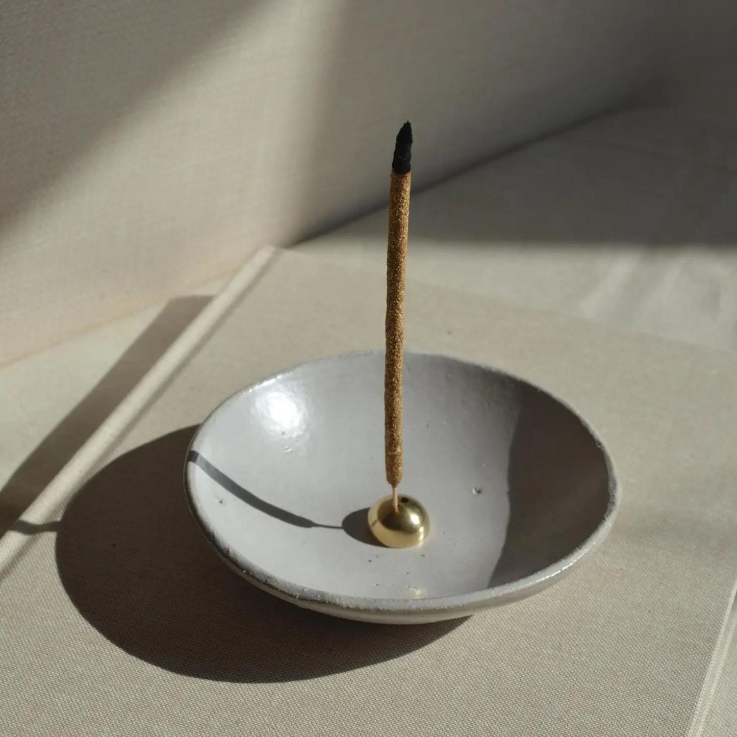 Brass Arch Incense Holder in a ceramic bowl to catch the burned pieces of the incense stick.