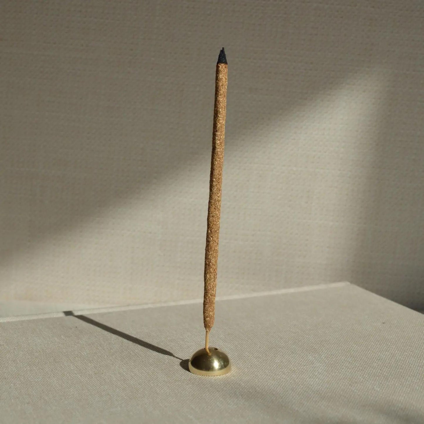 Brass Arch Incense Holder in a minimalist golden dome shape with a burning Incense Stick in it.