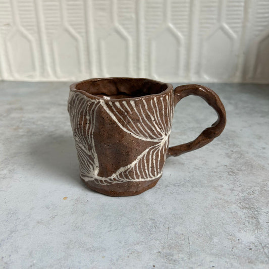 A brown mug with a white line pattern.