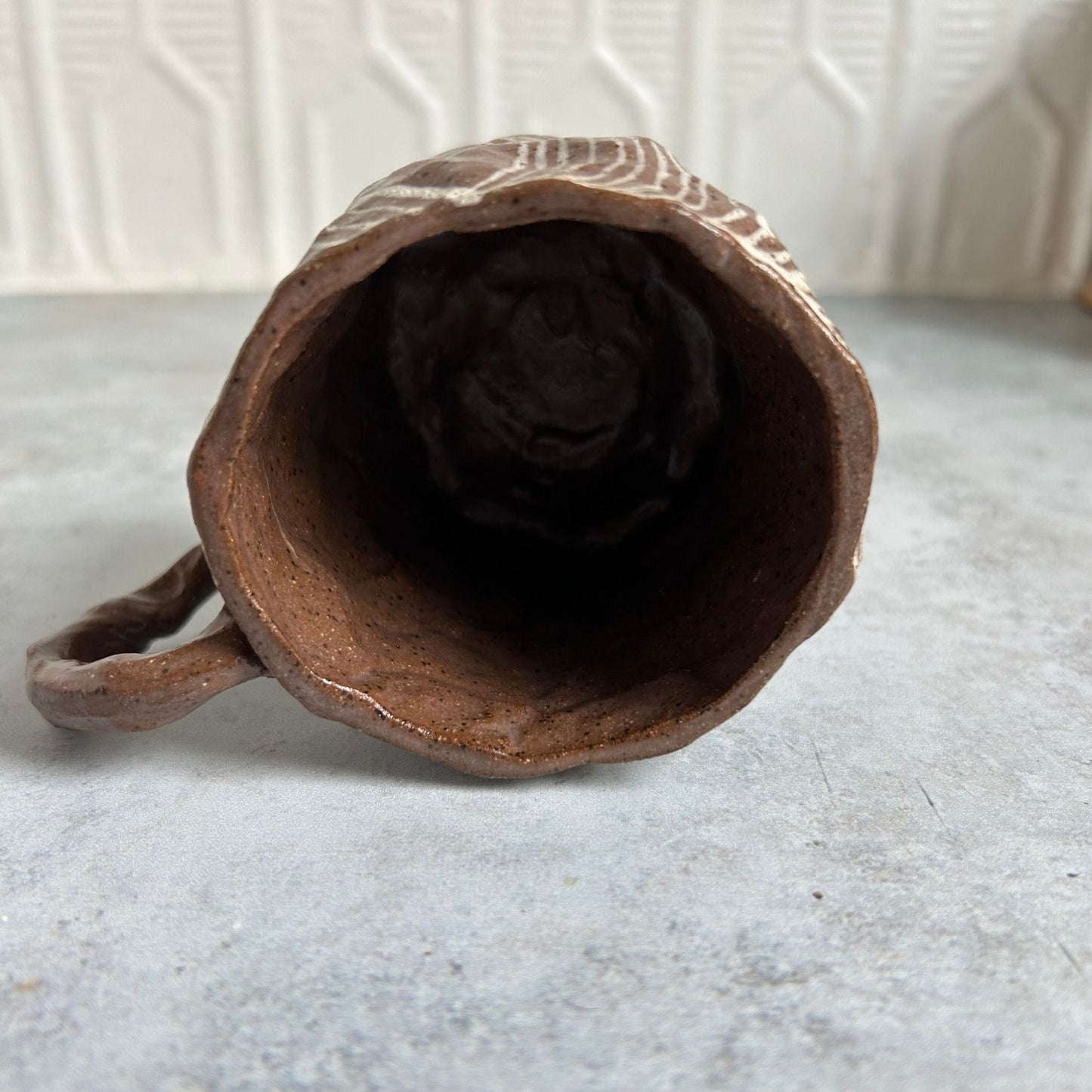 The inside of brown mug with a white line pattern.