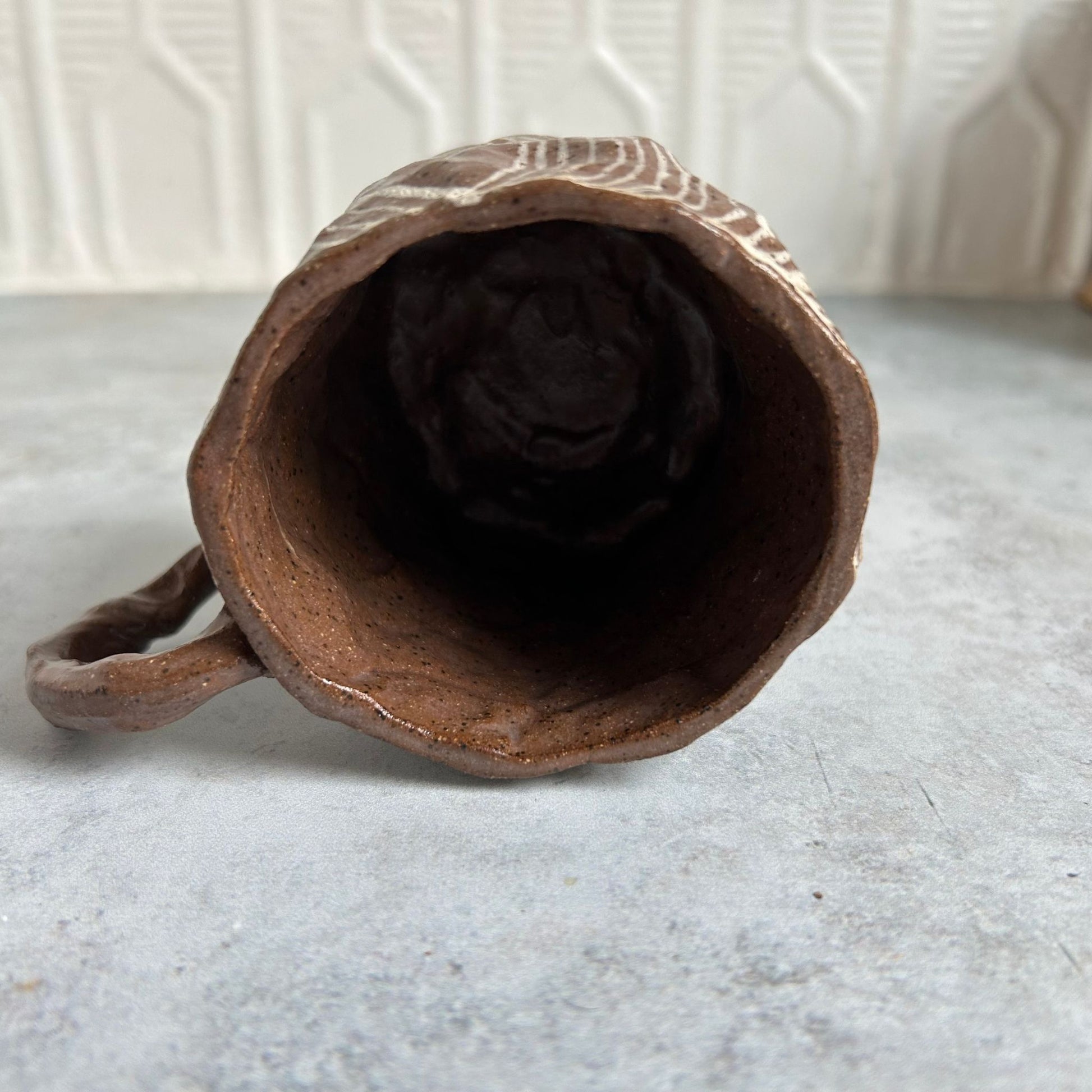 The inside of brown mug with a white line pattern.