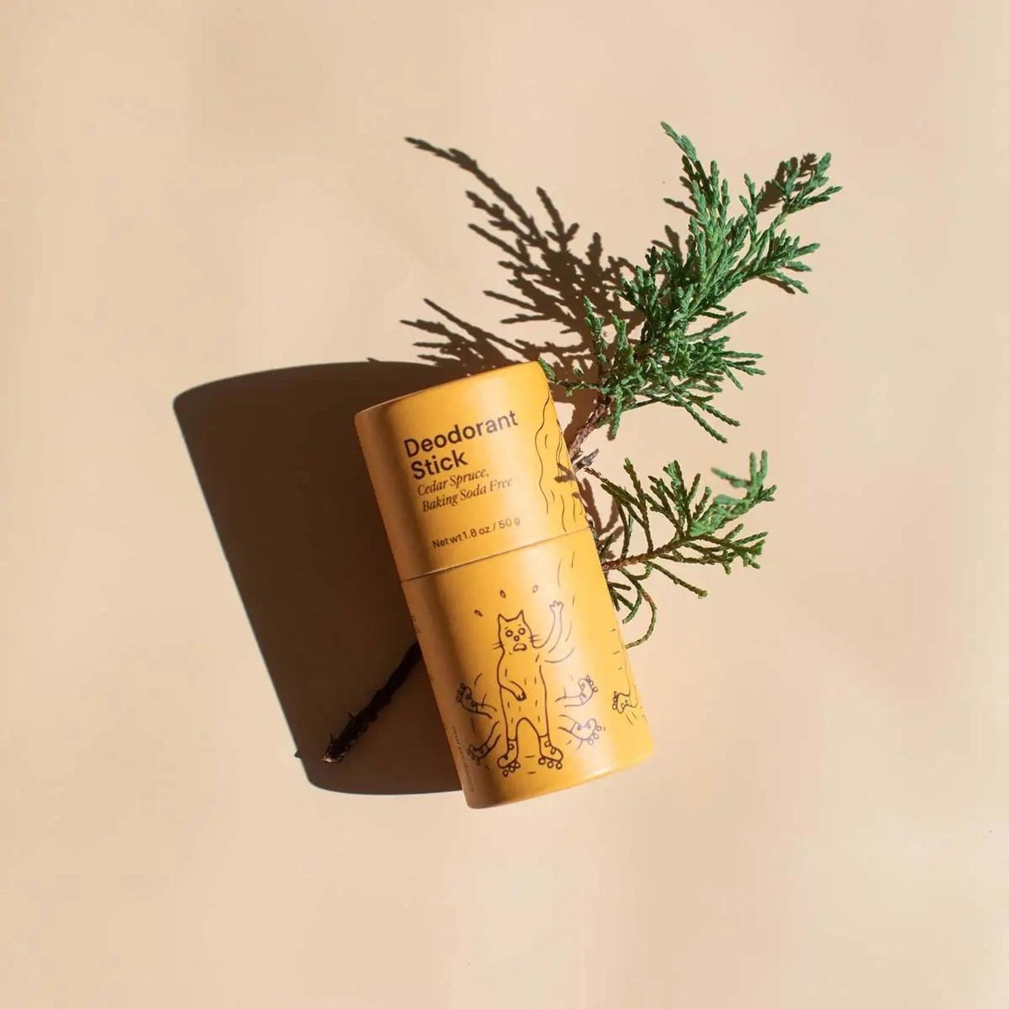 Cedar Spruce Baking Soda Free Deodorant Stick resting on a cedar branch