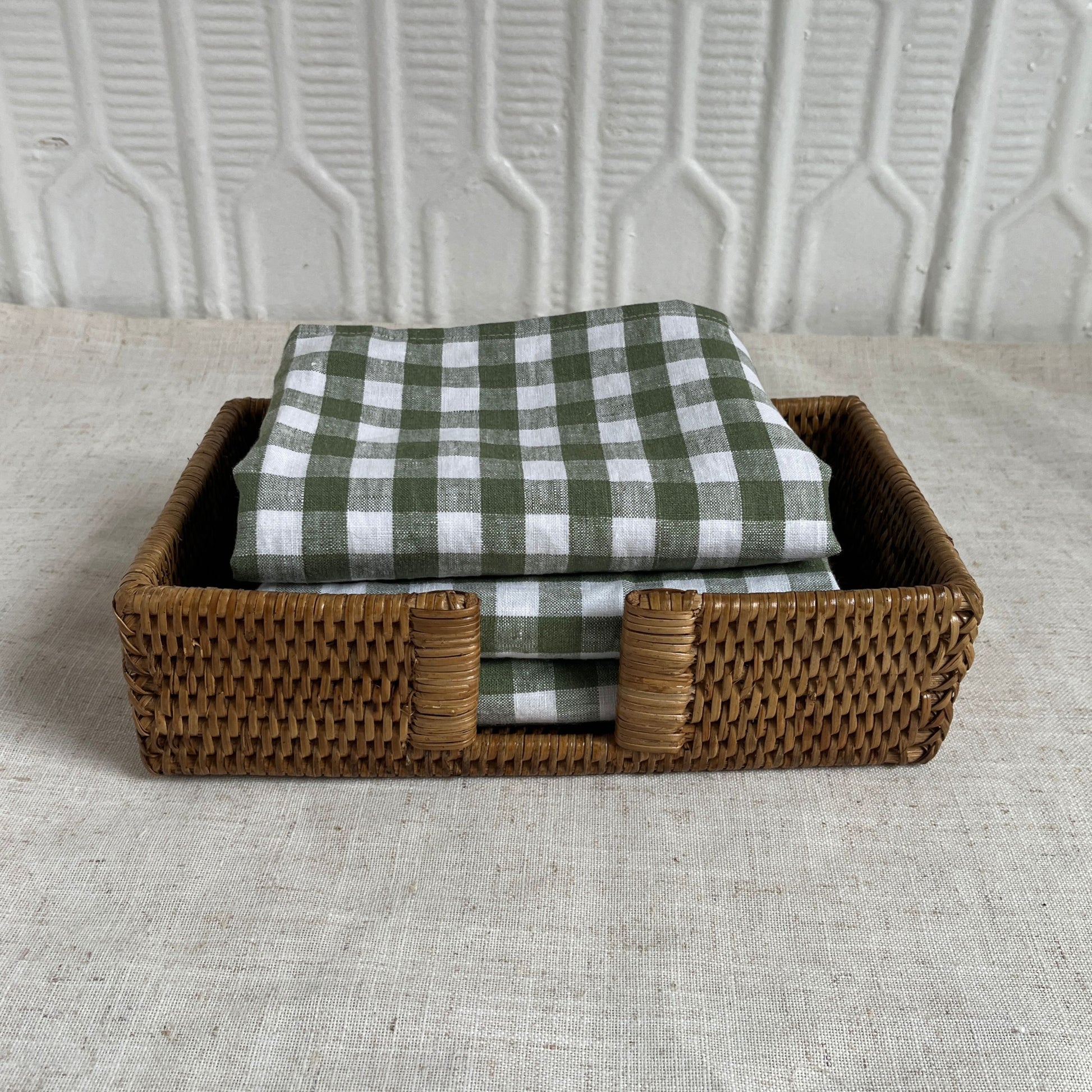 Woven basket with green and white checkered cloths on a textured surface
