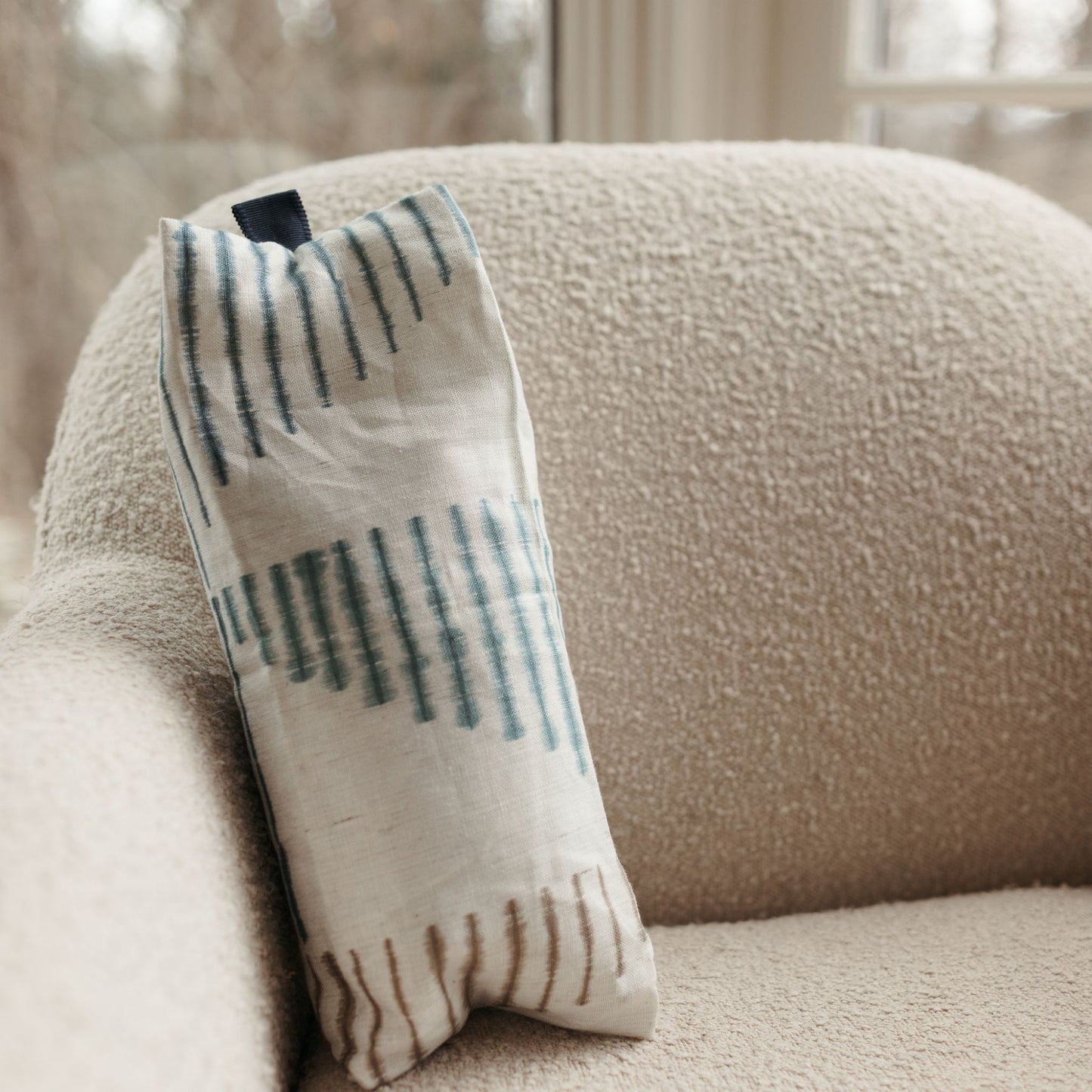 Buckwheat Pillow with ikat stripes resting on a sofa. The cover is 100% linen.