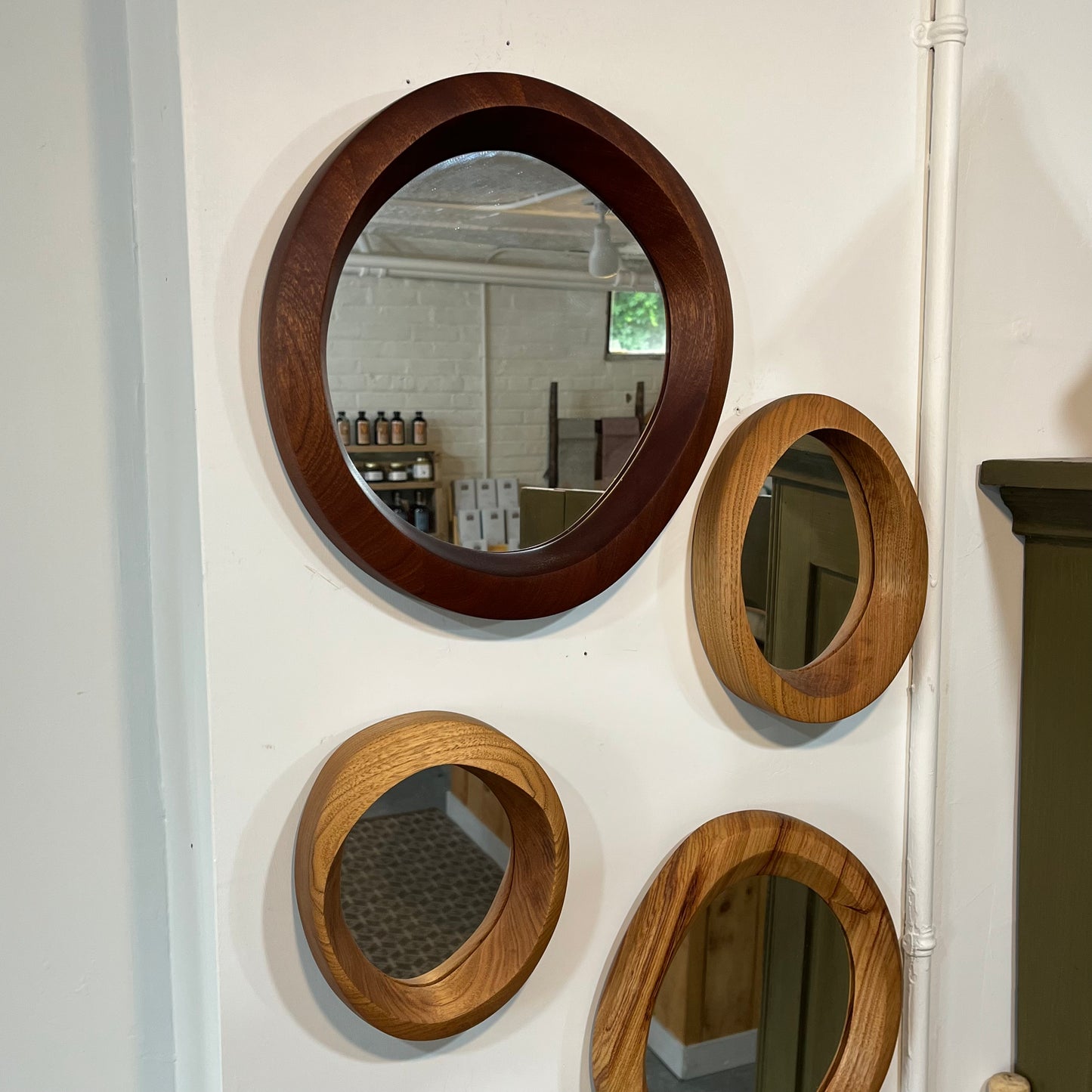 various sizes of hand-carved wooden wall mirrors each with one-of-a-kind organic shape and curves shown in butternut cherry and walnut