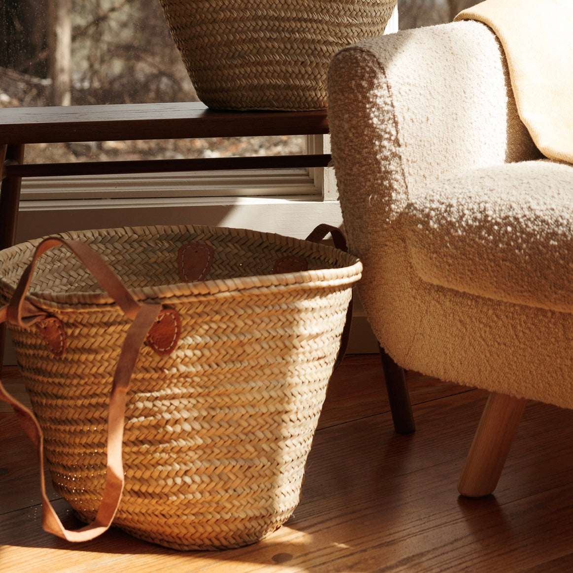 French Market Tote Basket sitting on the floor next to an armchair