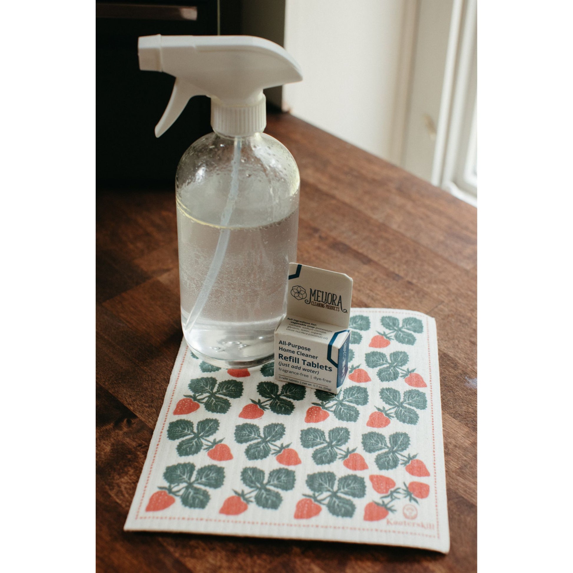 box of water-dissolvable all-purpose home cleaning tablets shown with a reusable glass spray bottle and a dish cloth