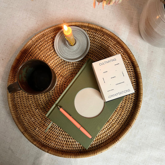 Wicker tray with a mug, notebook, pen, and candle on a light surface