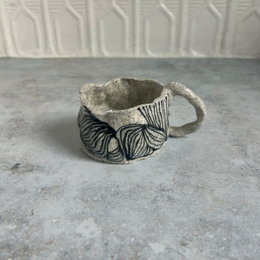 White speckled mug with black line pattern.