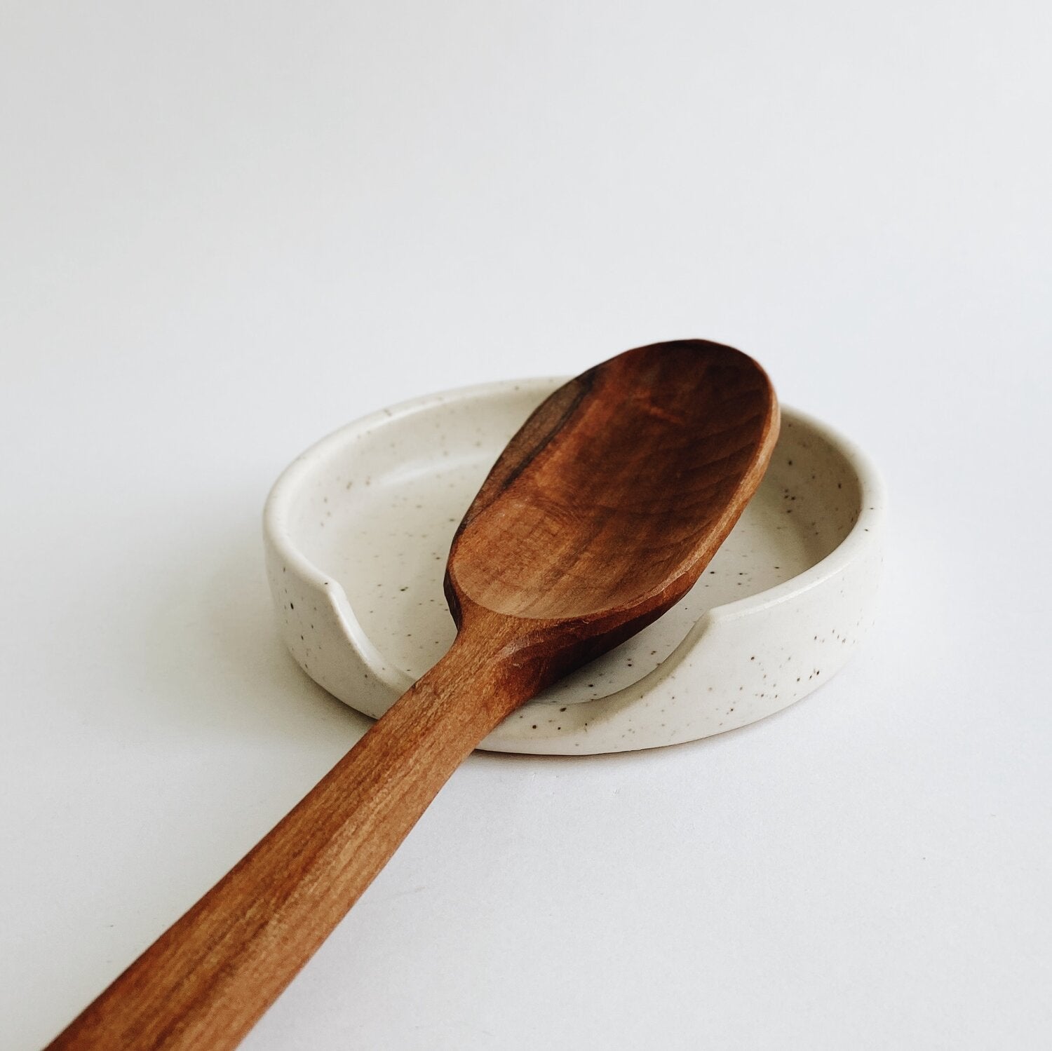 wooden spoon on ceramic Spoon rest in white speckled glaze 
