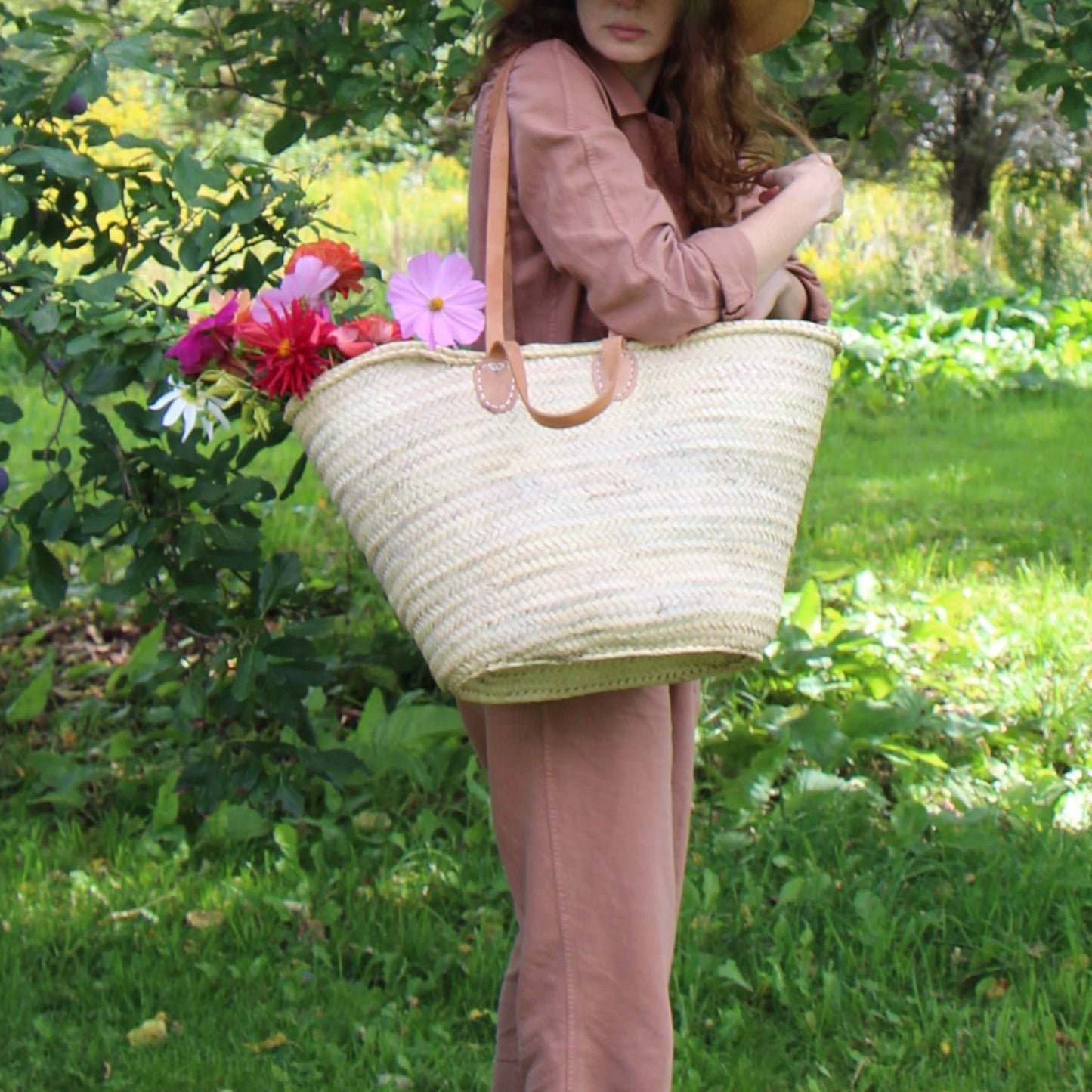French Market Tote Basket with flowers in it carried by a woman