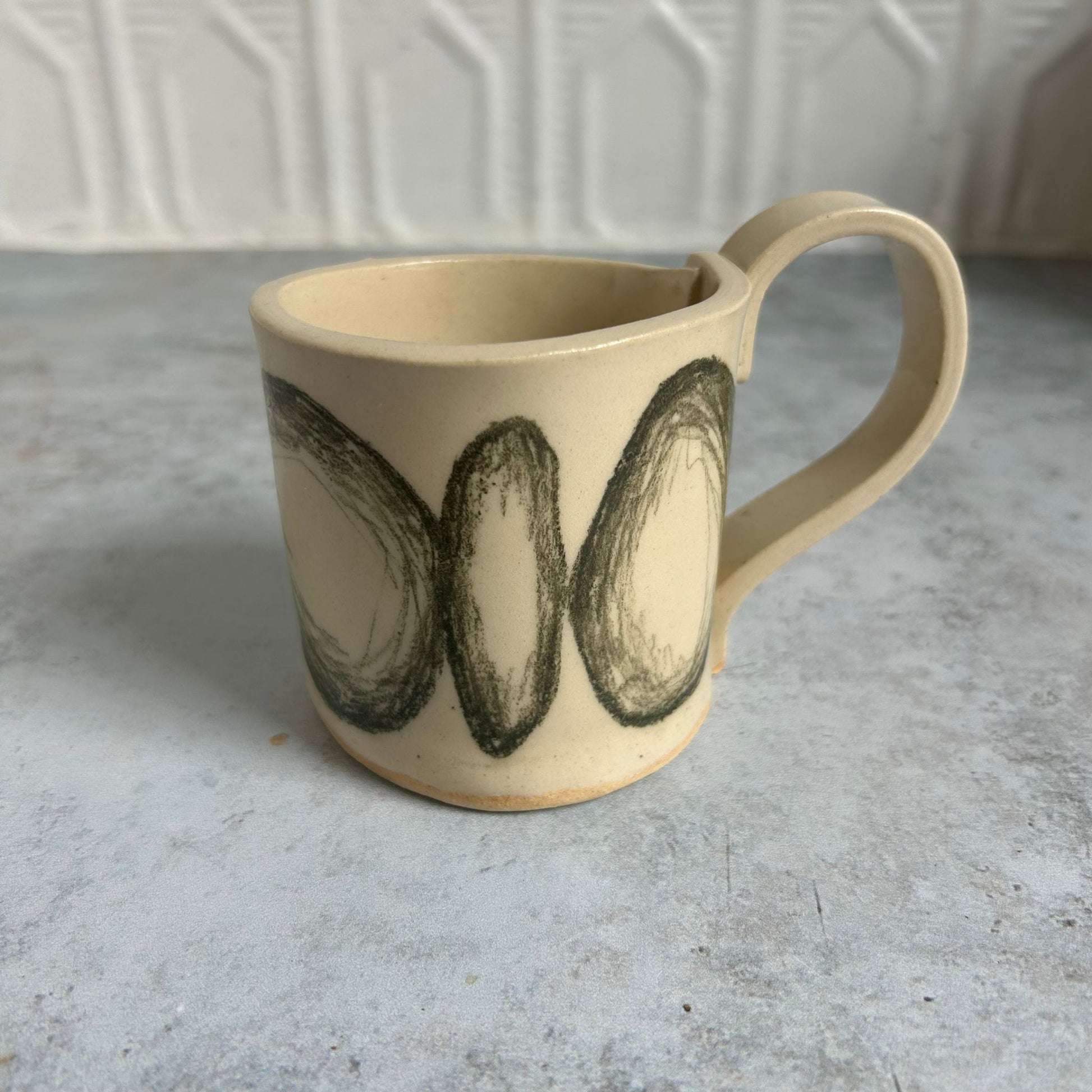 White mug with black drawn circles all around it.