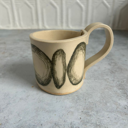 White mug with black drawn circles all around it.