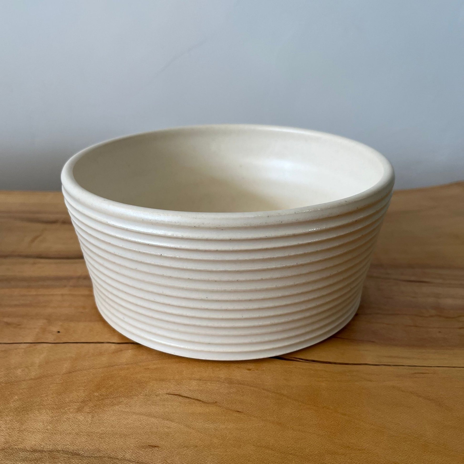 Wheel-thrown ribbed ceramic stoneware dinner bowl with handmade glaze in white color. 6" x 2.5"