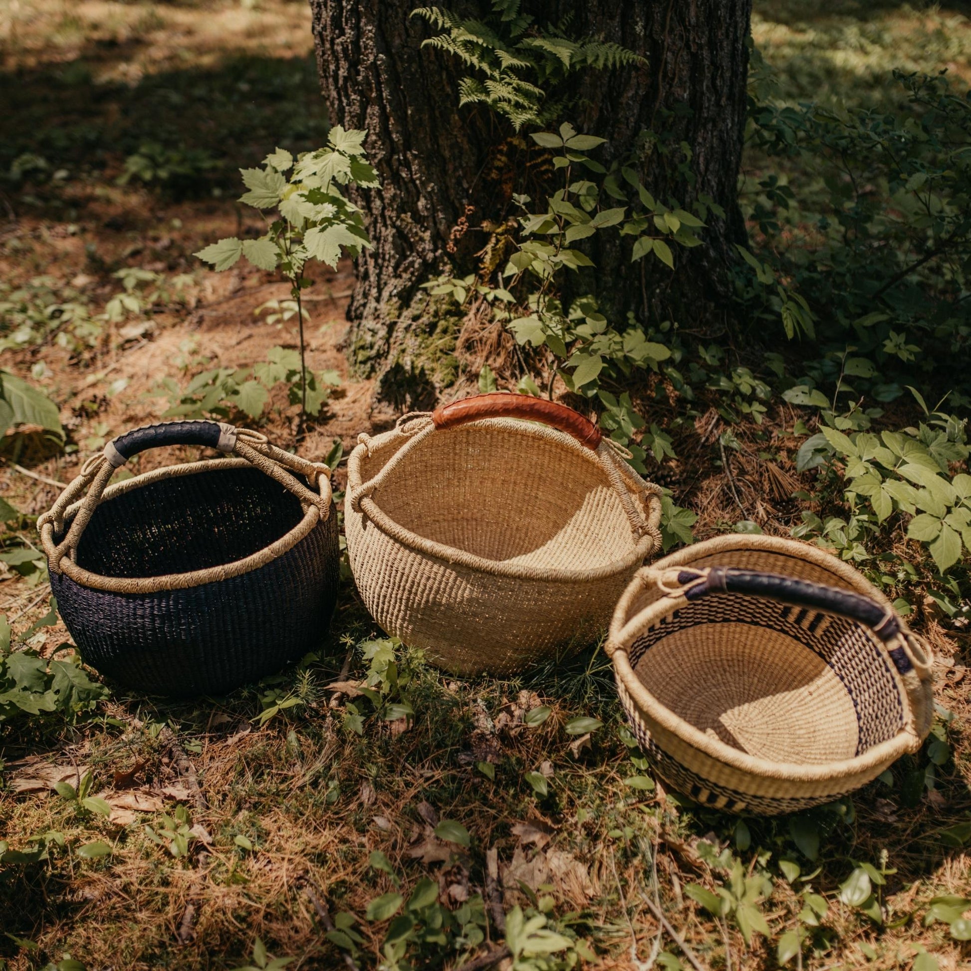 3 large Bolga baskets shown outdoors in black, natural, and patterned