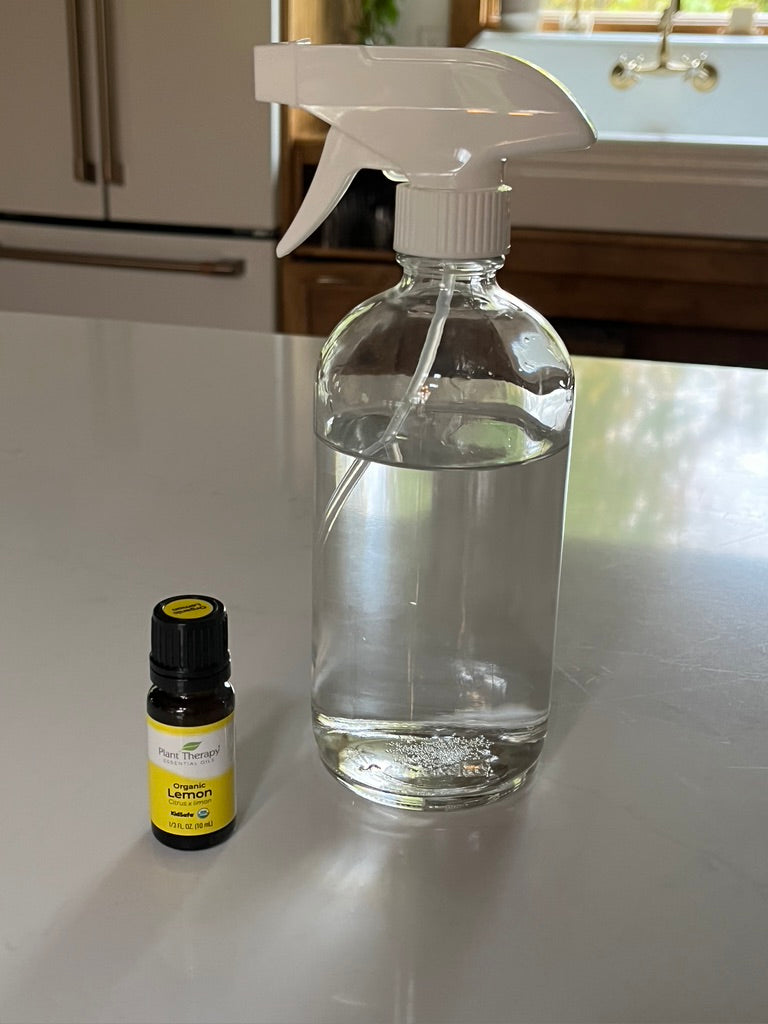 Refillable 16-ounce clear glass spray bottle with bottle of lemon essential oil