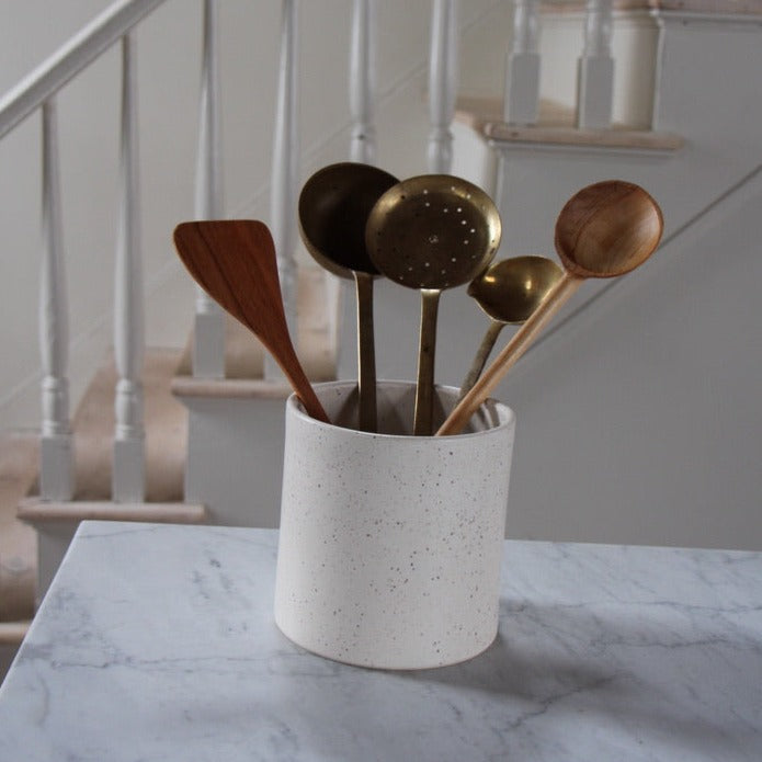 5 inch tall ceramic stoneware crock in white speckle glaze pictured with wood and metal cooking utensils