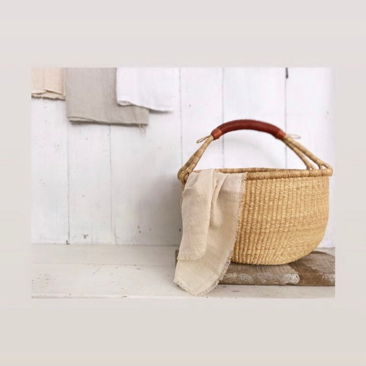 Soft stonewashed linen napkin with fringe edge shown in ivory with basket