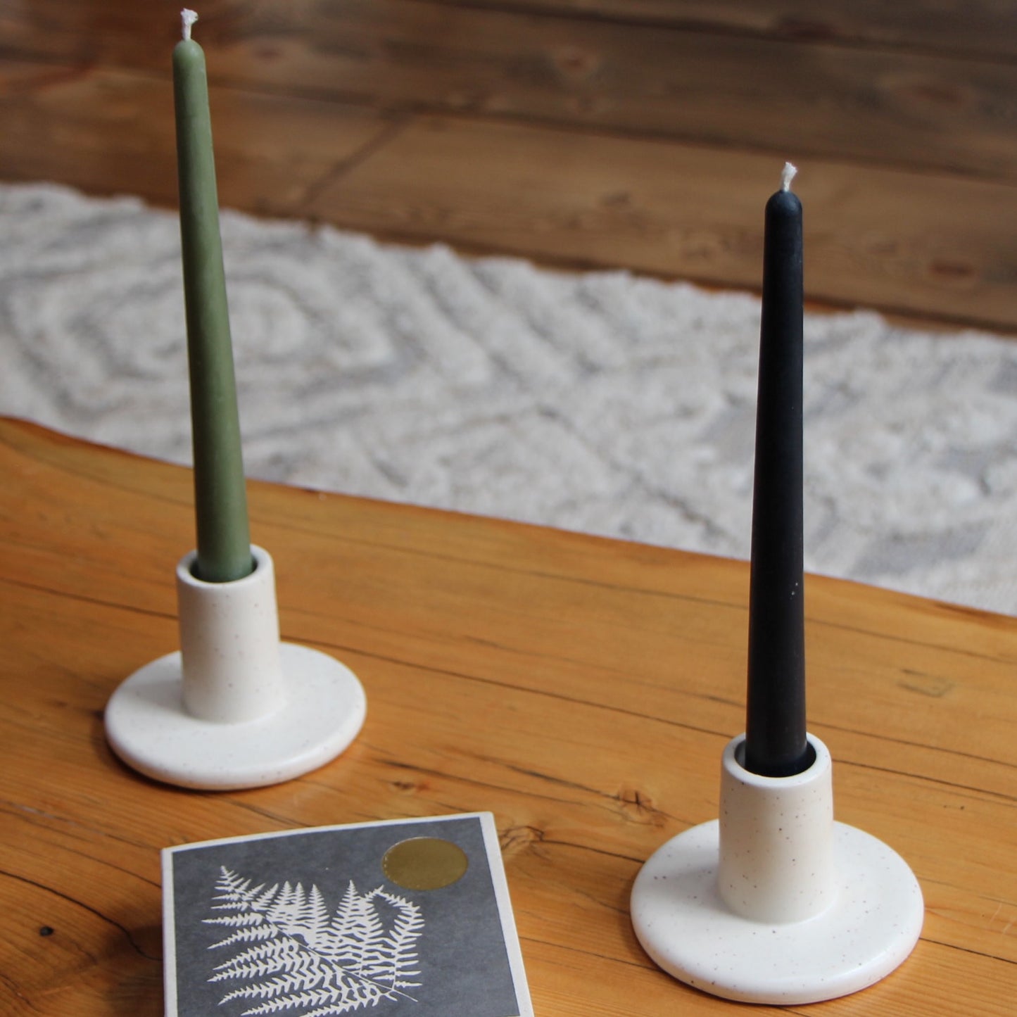 10-inch tall smooth taper candles made with locally-sourced beeswax, cotton wicks, and natural dye shown in ceramic candlesticks