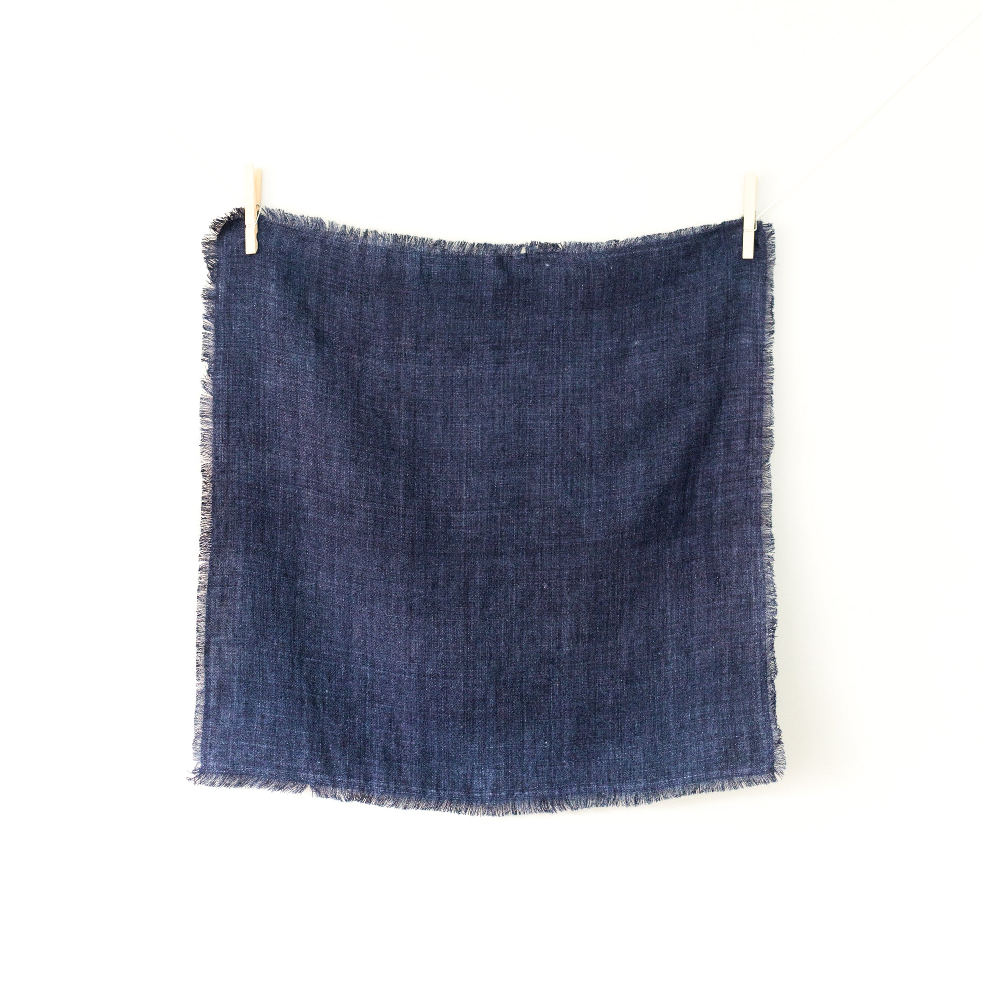 20-inch square stonewashed linen napkins with fringe edge shown hanging on clothesline