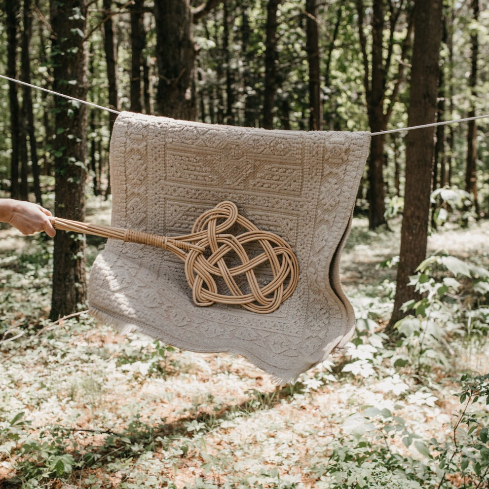 carpet beater cleaning a rug on a clothes line