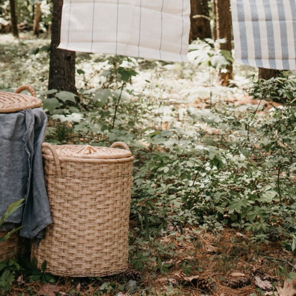 Lidded rattan storage baskets with handles shown in use outdoors with clothesline