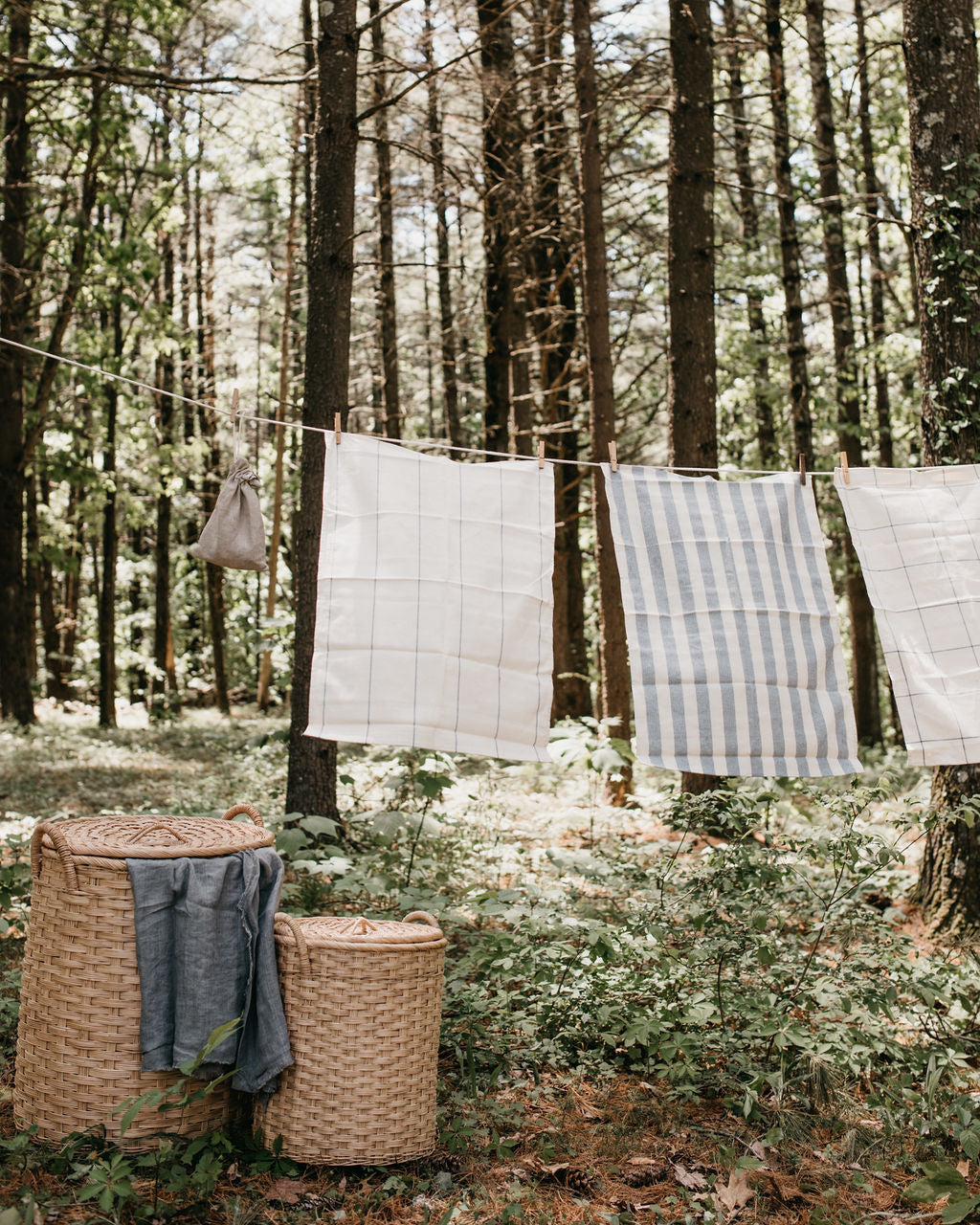 Laundry baskets under outdoor clothesline with wooden clothespins and linens drying