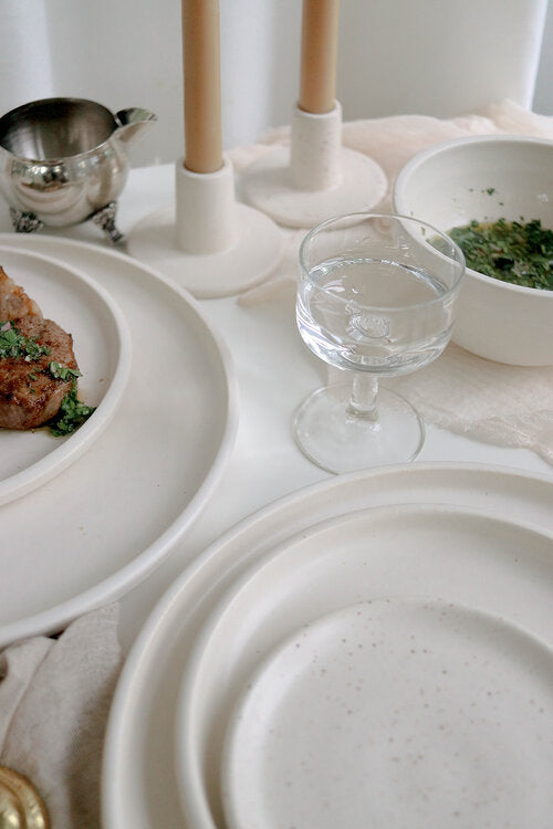 2 wheel-thrown stoneware ceramic candlesticks with white speckle glaze on a  laid table