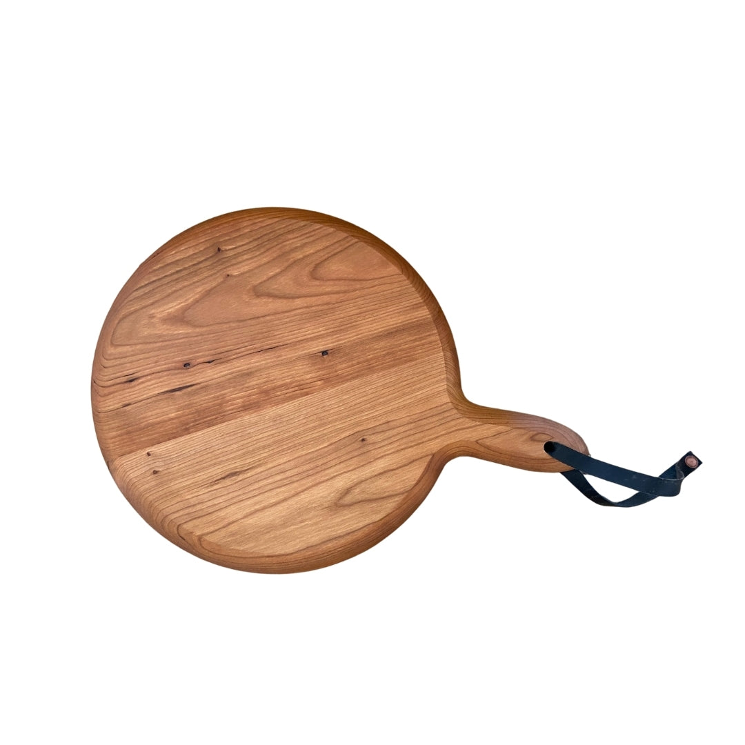 Large circular cutting board in cherry wood with handle and leather strap