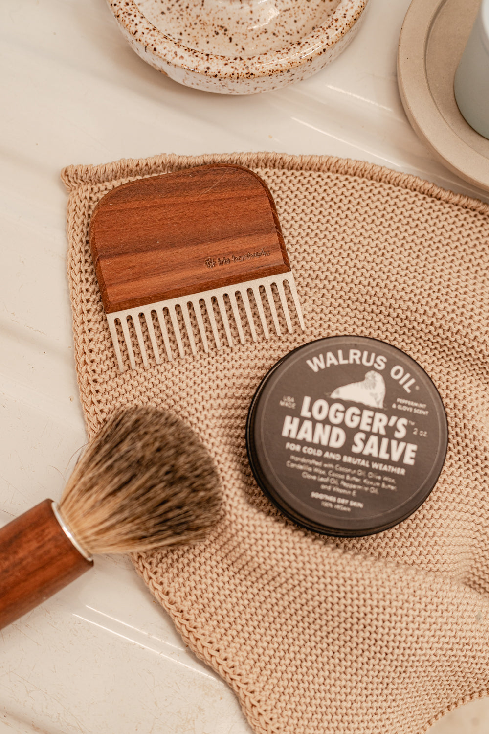 Tin of logger's hand salve pictured with beard comb and shaving cream brush