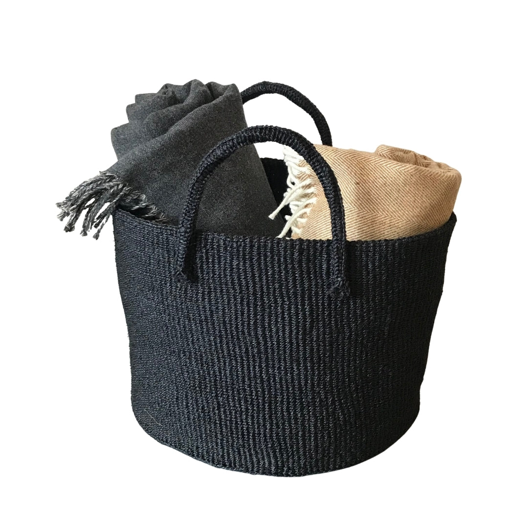 Large round flexible Sisal basket with handles in black shown with throw blankets inside