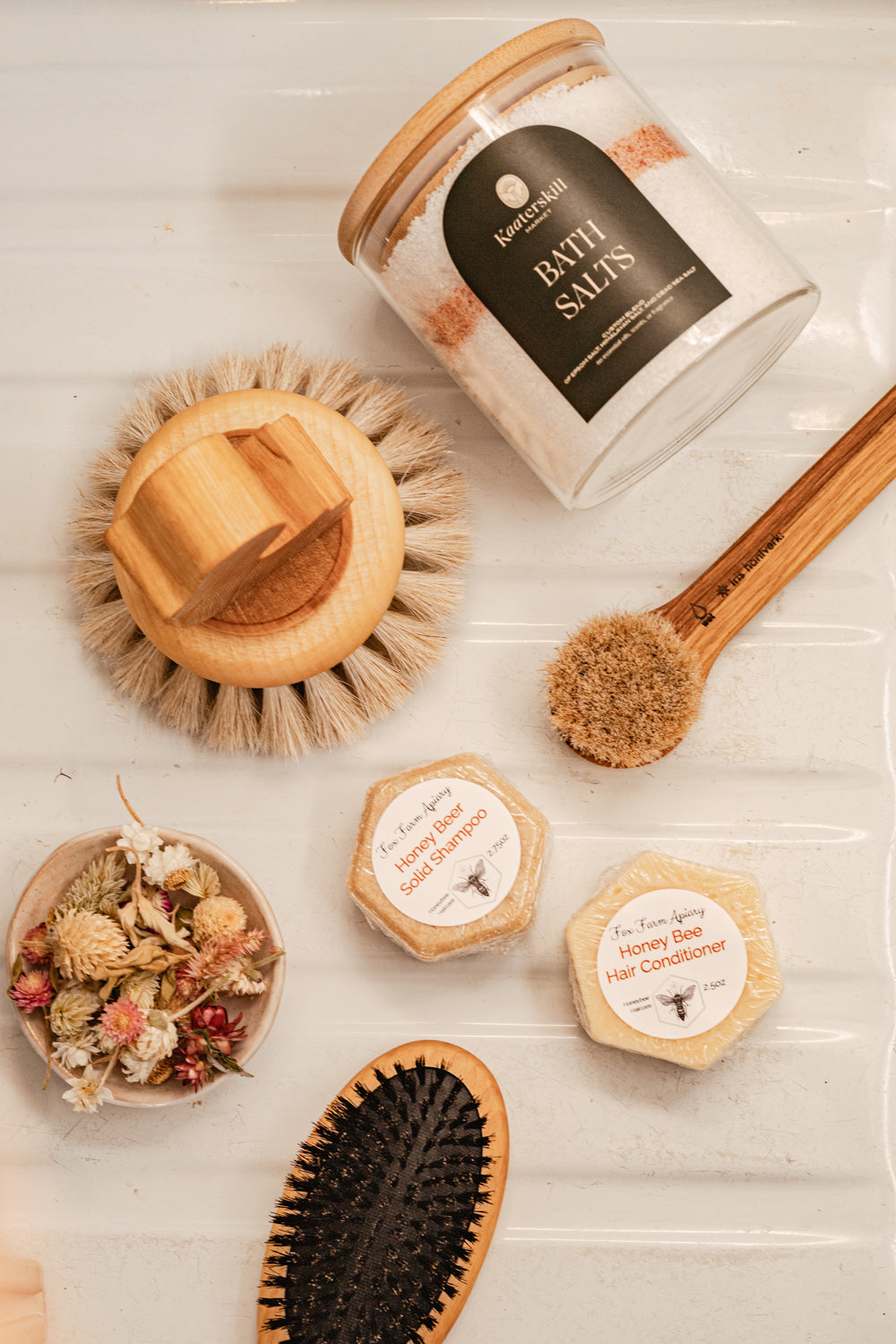 soft face washing brush made of horsehair and oak wood handle shown with bath salts, bar shampoo and conditioner, duck bath brush, and boar bristle hair brush
