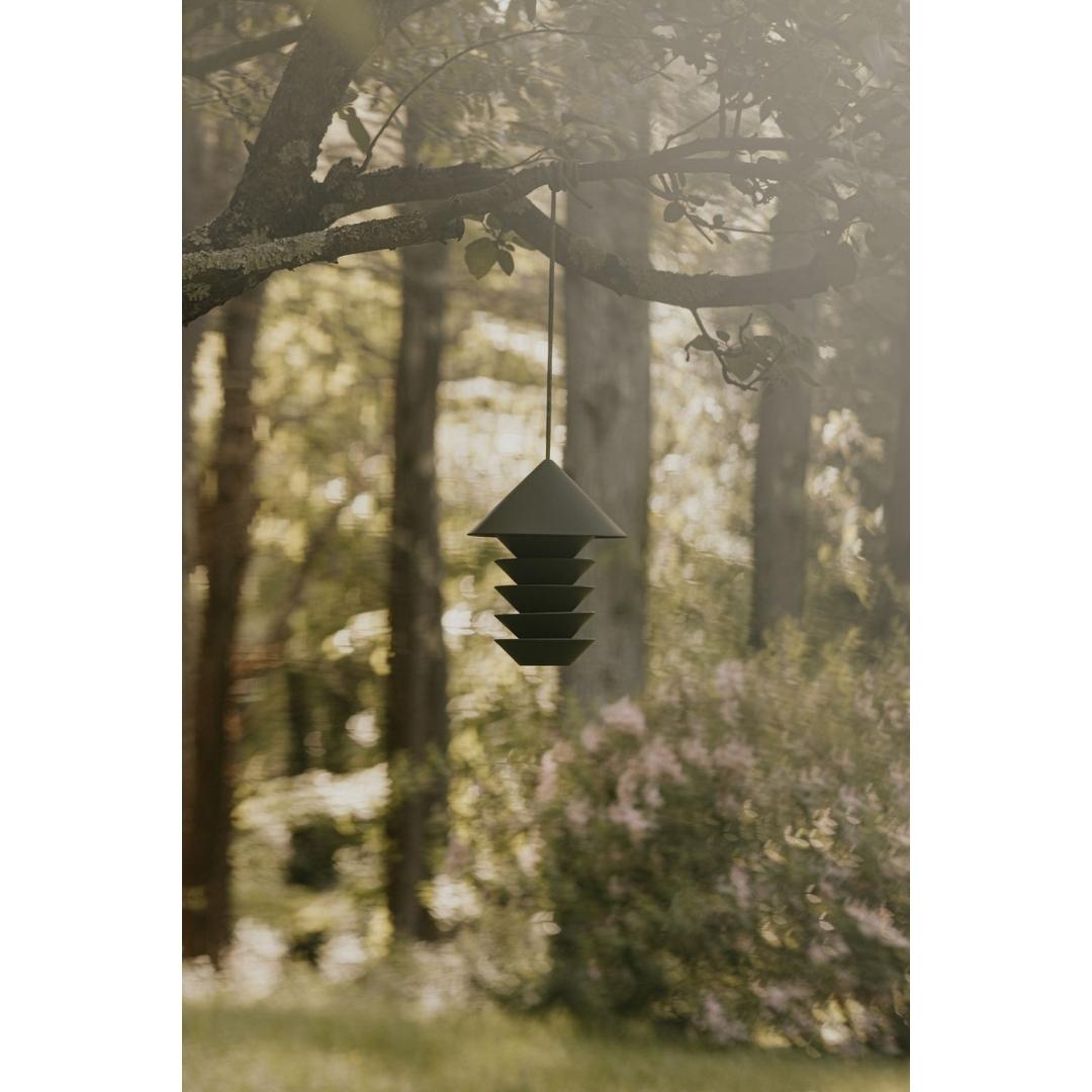 green modern bird feeder hanging from a tree branch