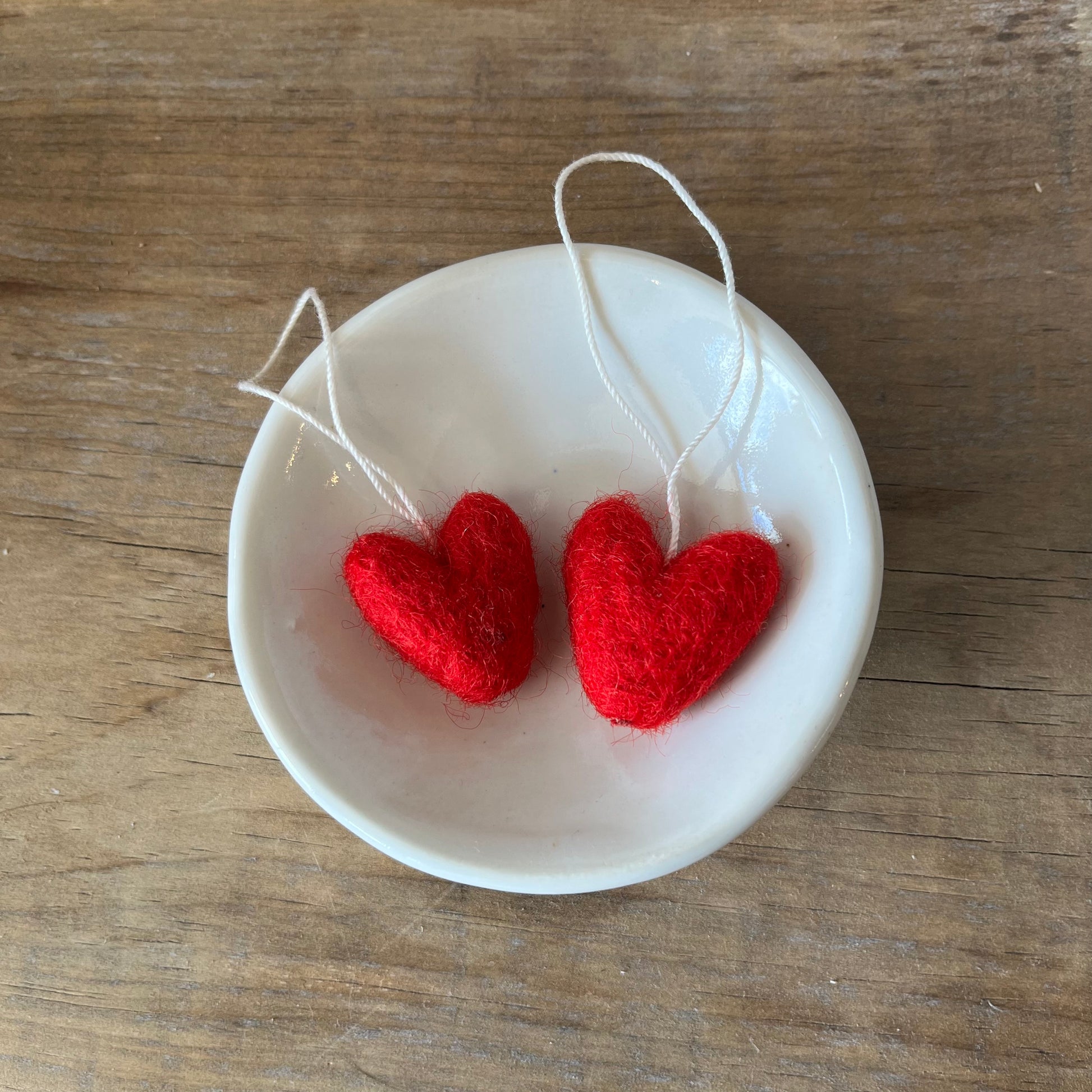 Handmade felted wool red hearts in a small bowl