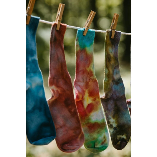 Vibrantly colored ice-dyed cotton socks hanging on a clothesline with clothespins