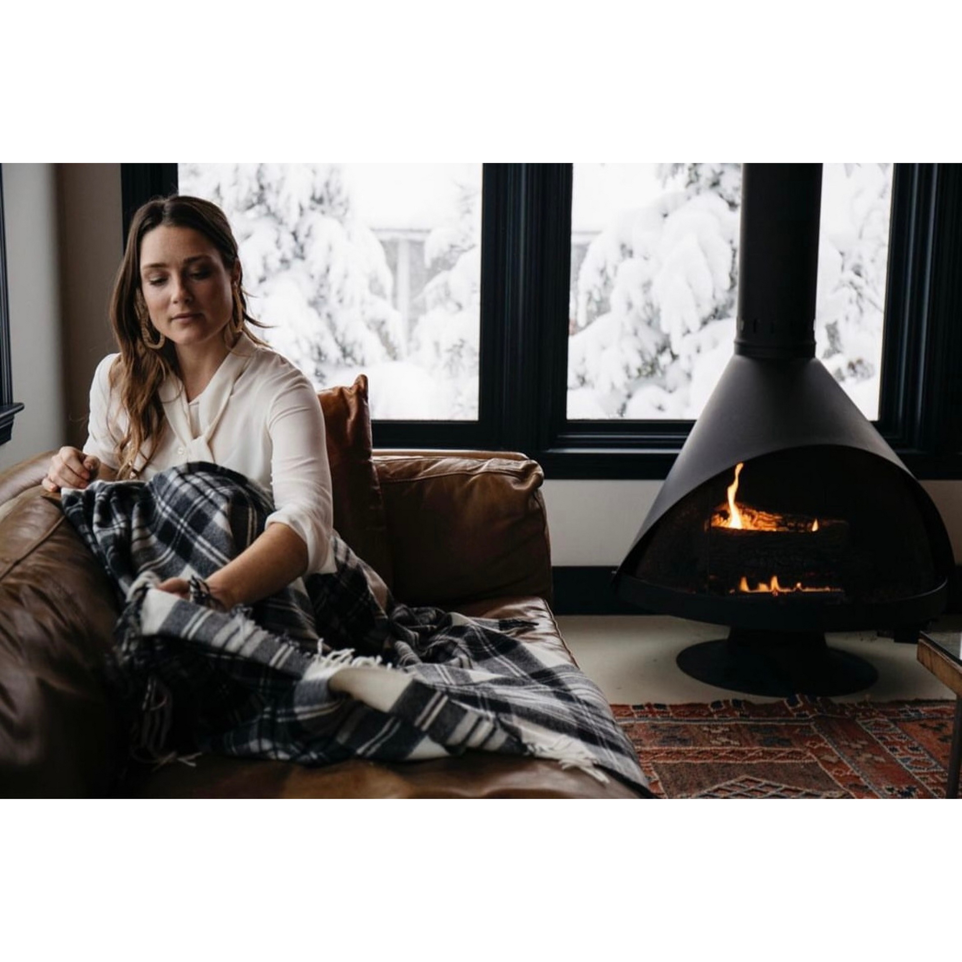 woman on sofa wrapped in a blanket with a fireplace