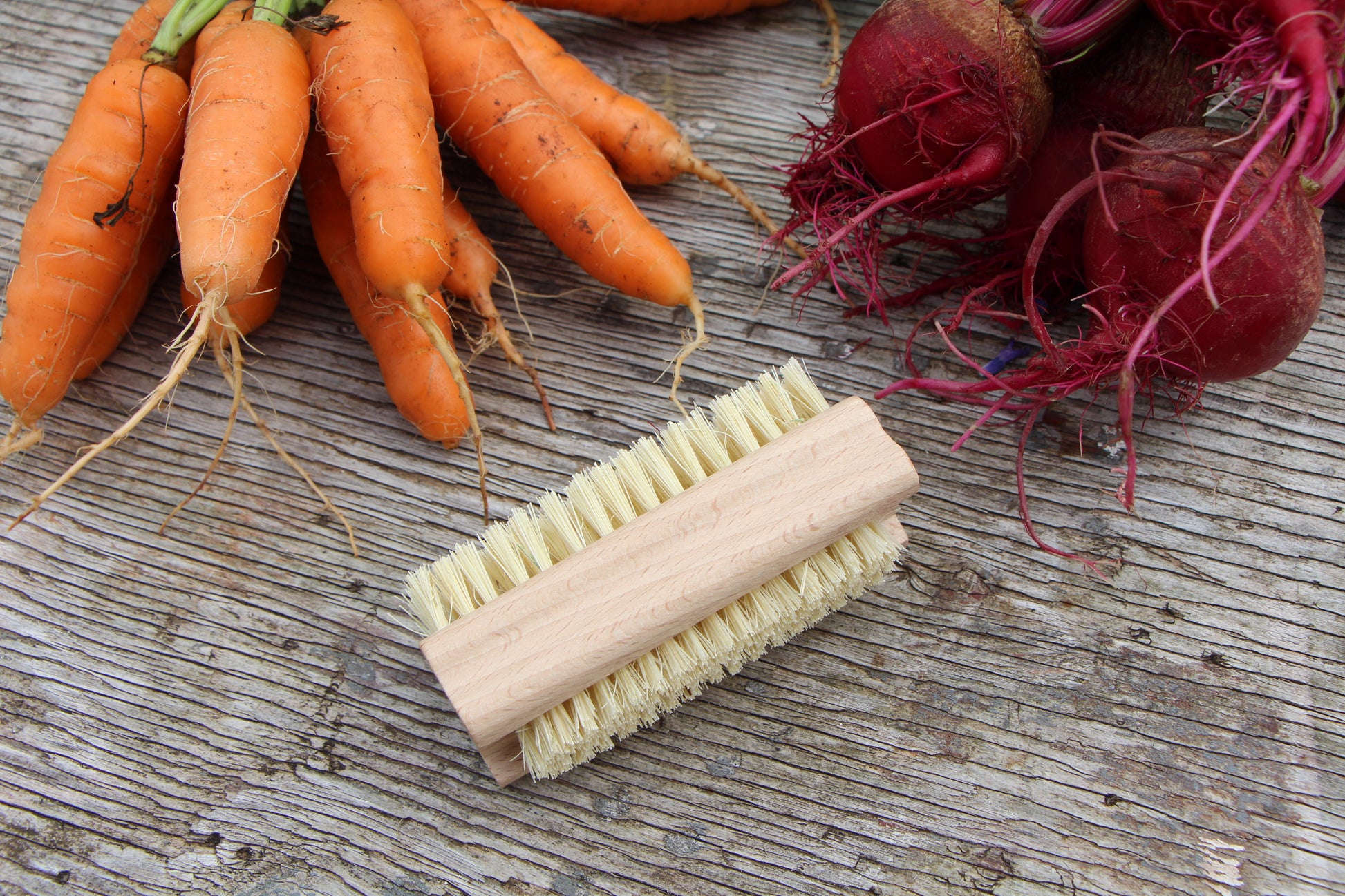 Double-sided scrub brush made of Tampico fibers and Ash wood pictured with beets and carrots