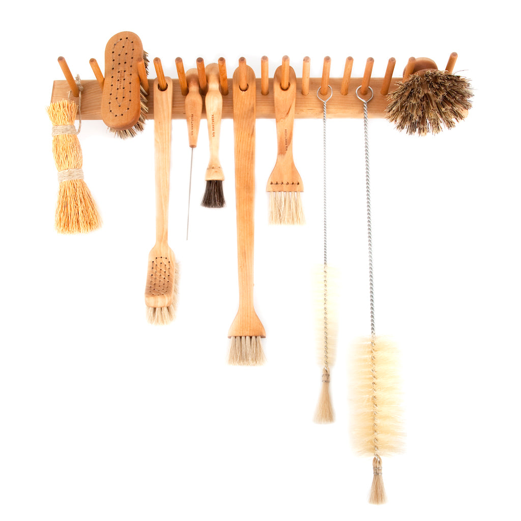 Narrow and long bottle cleaning brushes shown hanging on a wall-mounted peg rail