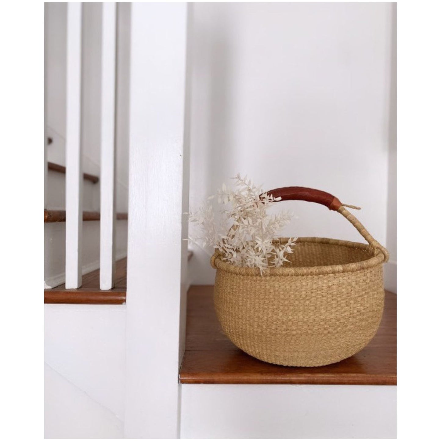 large natural Bolga basket with leather handle and dried flowers on stairs