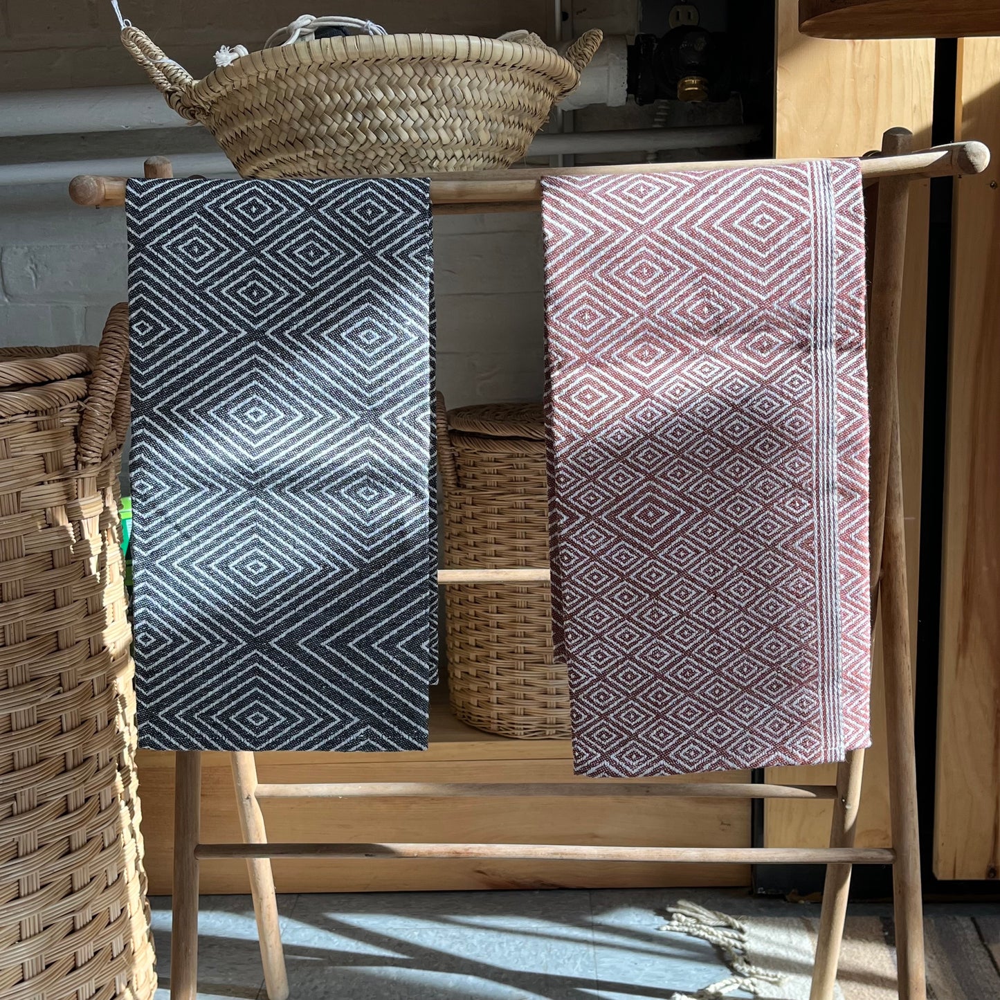 Two linen tea towels in classic diamond pattern hanging on wooden rack