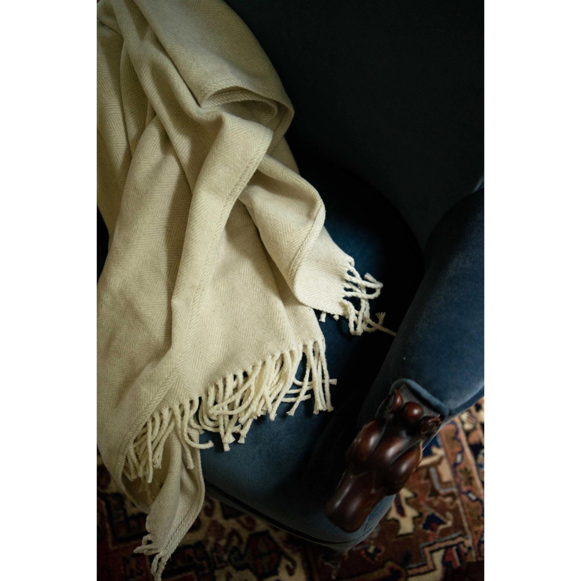 Brushed cotton throw blanket with herringbone pattern in oyster gray draped on armchair