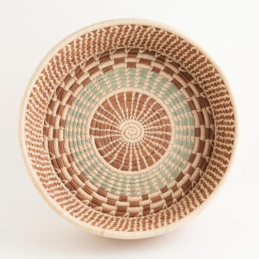 An above shot of a brown, tan, and light green handwoven pine needle harvest basket. 