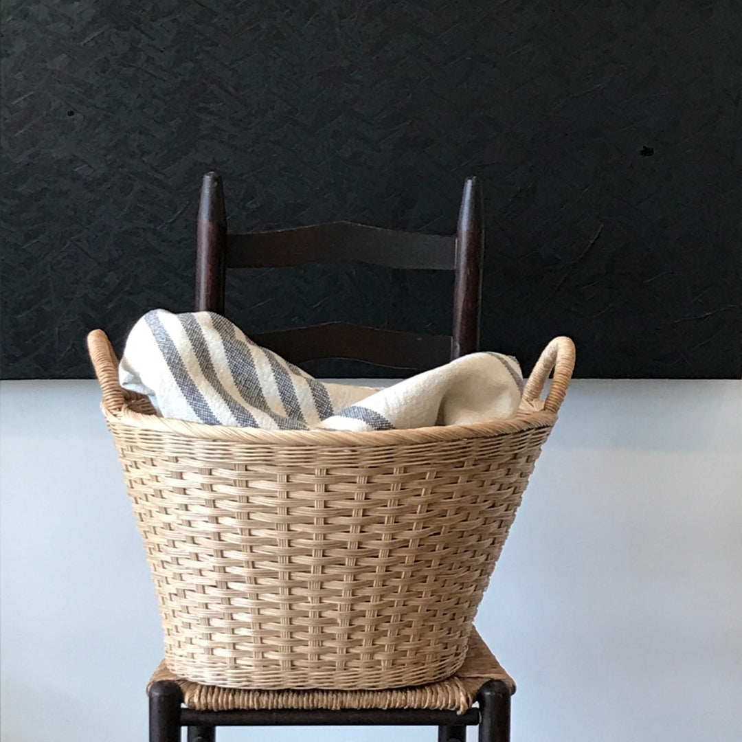 rattan laundry basket filled with linens on a chair