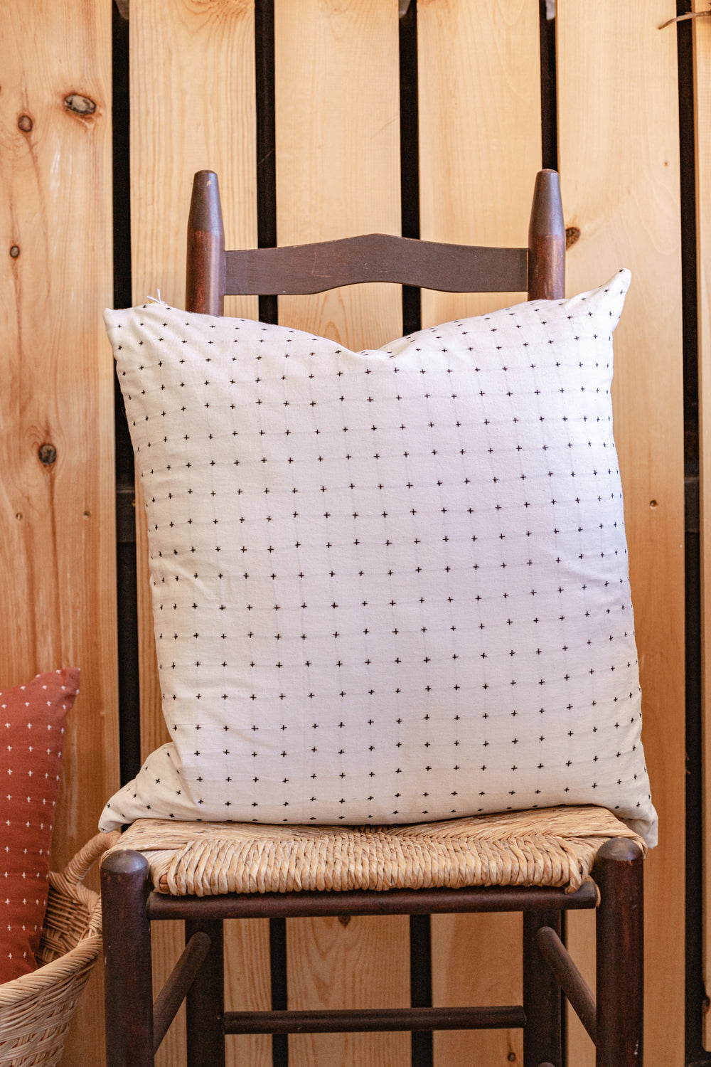 Hand-embroidered cotton square throw pillows in bone white color on wooden chair